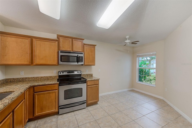 15410 Quail Woods Pl, Ruskin, FL 33573 - kitchen featuring light stone counters, a textured ceiling, brown cabinetry, ceiling fan, and appliances with stainless steel finishes