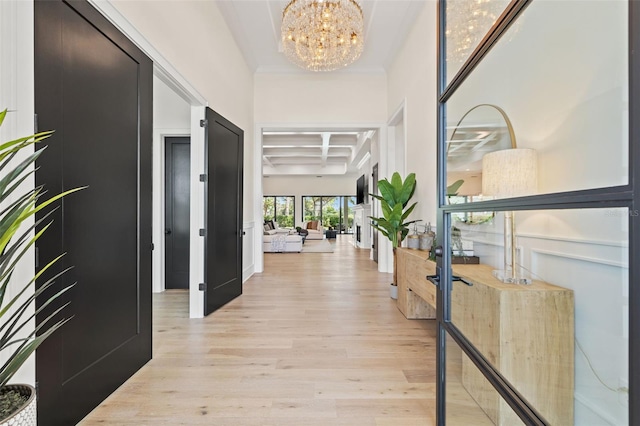 corridor with coffered ceiling, beamed ceiling, light wood-type flooring, and a notable chandelier