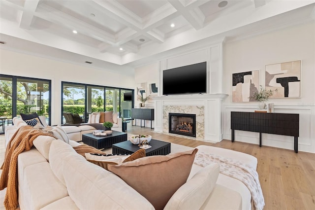 living room with a fireplace, beamed ceiling, a towering ceiling, light wood-style flooring, and coffered ceiling