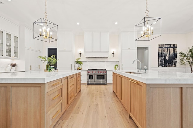 kitchen with a sink, double oven range, a notable chandelier, and a spacious island