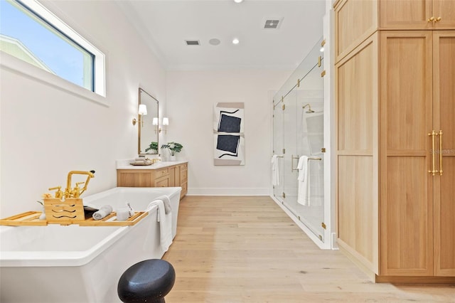 bathroom featuring a freestanding tub, a stall shower, wood finished floors, and vanity