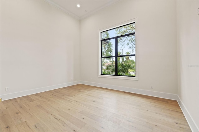 empty room with light wood-style floors, baseboards, and ornamental molding