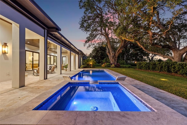 view of swimming pool with a patio, a yard, and a pool with connected hot tub