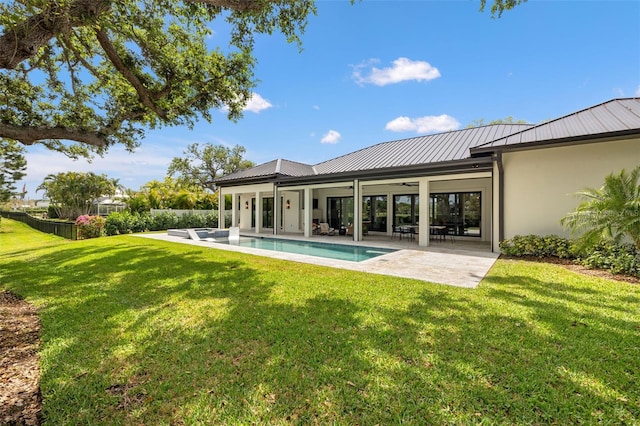 back of property with a ceiling fan, metal roof, a lawn, a patio, and a fenced in pool