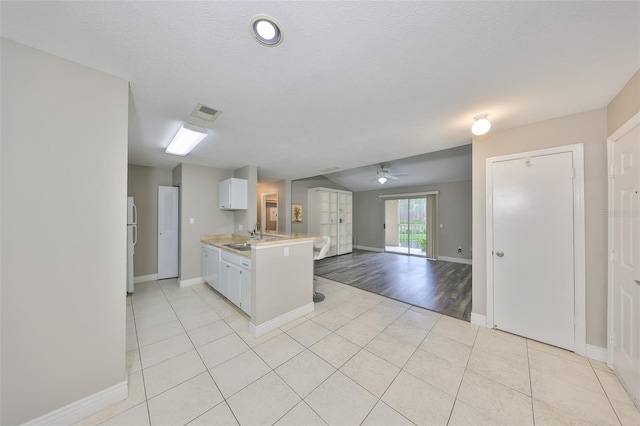 9481 Highland Oak Dr Unit 1206, Tampa, FL 33647 - kitchen with light countertops, light tile patterned floors, a peninsula, open floor plan, and white cabinets