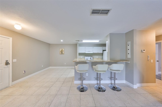9481 Highland Oak Dr Unit 1206, Tampa, FL 33647 - kitchen featuring a breakfast bar area, freestanding refrigerator, a peninsula, and light tile patterned flooring