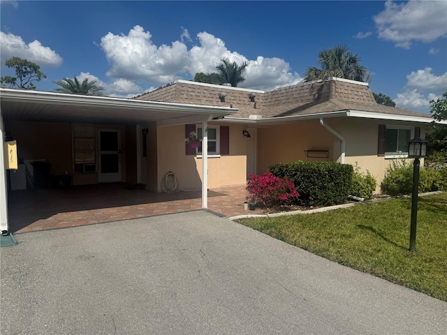 view of front of house featuring a carport, a front yard, aphalt driveway, and stucco siding