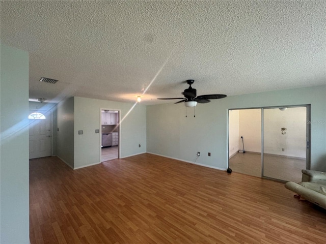 unfurnished living room featuring a textured ceiling, wood finished floors, ceiling fan, and visible vents