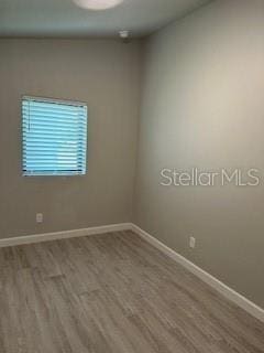 unfurnished room featuring baseboards and wood finished floors
