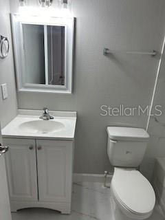 full bath with baseboards, a bathing tub, toilet, a shower, and vanity