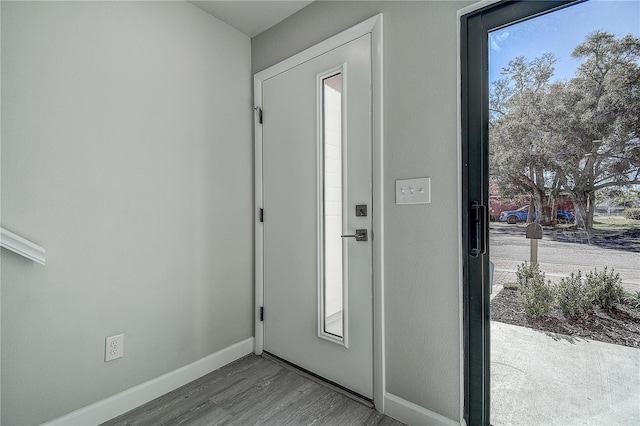 doorway featuring baseboards and wood finished floors