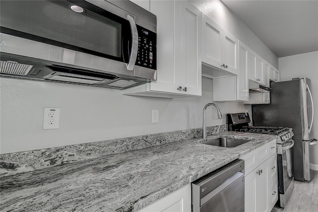 kitchen featuring appliances with stainless steel finishes, a sink, white cabinetry, and under cabinet range hood