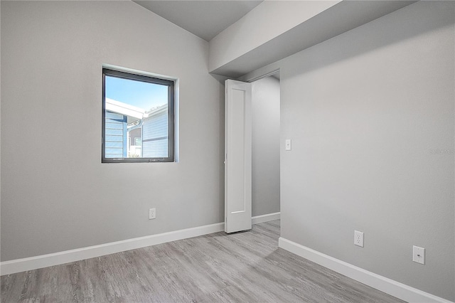 spare room with baseboards and wood finished floors