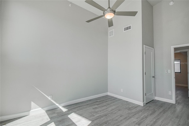 spare room featuring high vaulted ceiling, a ceiling fan, visible vents, wood finished floors, and baseboards