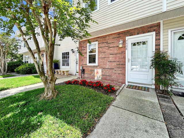 7508 Hollowell Dr, Tampa, FL 33615 - view of exterior entry with a yard and brick siding