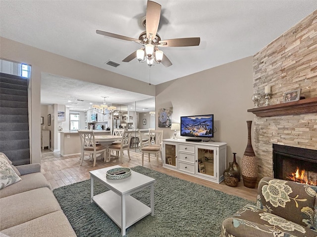 7508 Hollowell Dr, Tampa, FL 33615 - living room featuring visible vents, a stone fireplace, stairway, wood finished floors, and ceiling fan with notable chandelier
