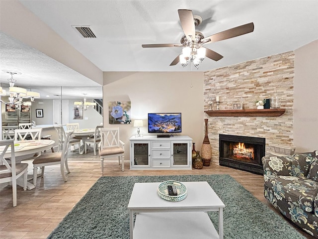 7508 Hollowell Dr, Tampa, FL 33615 - living area with wood finished floors, ceiling fan with notable chandelier, a stone fireplace, and visible vents