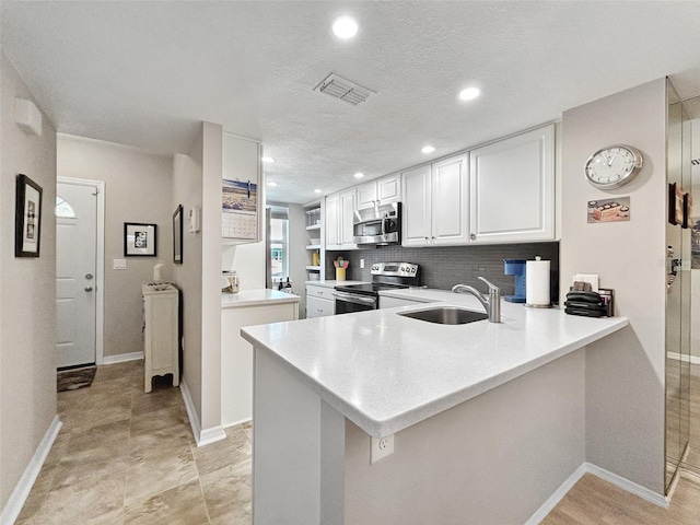 7508 Hollowell Dr, Tampa, FL 33615 - kitchen with visible vents, a sink, a peninsula, white cabinetry, and stainless steel appliances