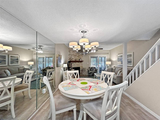 7508 Hollowell Dr, Tampa, FL 33615 - dining space featuring baseboards, a textured ceiling, light wood-style floors, and ceiling fan with notable chandelier