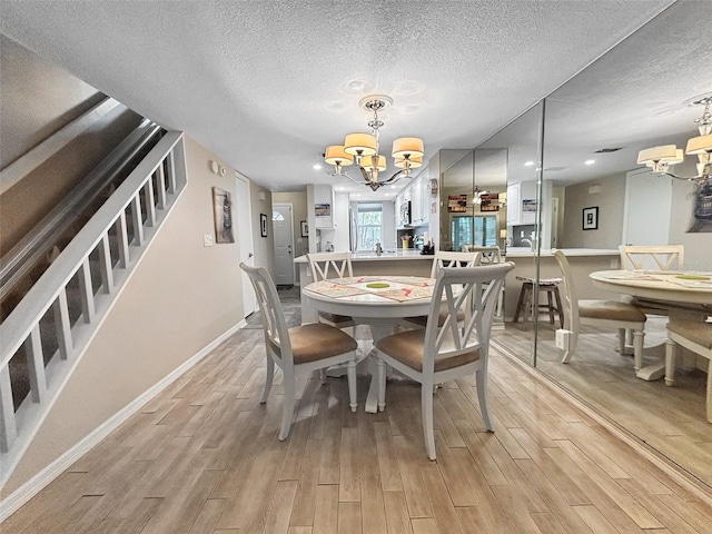 7508 Hollowell Dr, Tampa, FL 33615 - dining space with baseboards, a chandelier, light wood-style floors, and a textured ceiling
