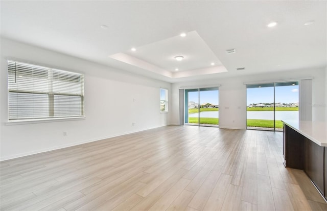 10317 Cross River Trl, Parrish, FL 34219 - empty room featuring a tray ceiling, light wood-style floors, recessed lighting, and a water view