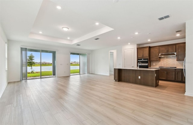 10317 Cross River Trl, Parrish, FL 34219 - kitchen with open floor plan, a raised ceiling, tasteful backsplash, light wood-style flooring, and recessed lighting