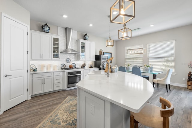 4365 Frontera Ln, Wesley Chapel, FL 33543 - kitchen featuring a sink, a kitchen bar, backsplash, wall chimney exhaust hood, and appliances with stainless steel finishes