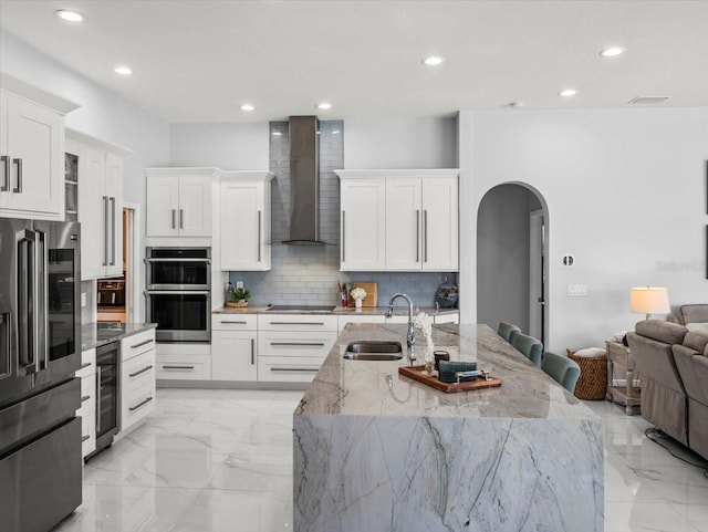 1084 Berkshire Ln, Tarpon Springs, FL 34688 - kitchen with a sink, appliances with stainless steel finishes, beverage cooler, wall chimney exhaust hood, and arched walkways