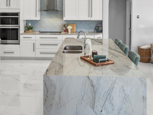 1084 Berkshire Ln, Tarpon Springs, FL 34688 - kitchen featuring wall chimney range hood, stainless steel double oven, a sink, black electric stovetop, and white cabinets