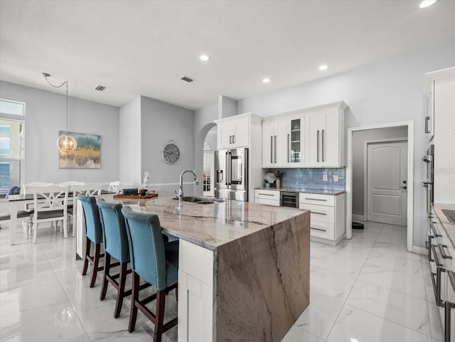 1084 Berkshire Ln, Tarpon Springs, FL 34688 - kitchen featuring appliances with stainless steel finishes, a sink, arched walkways, recessed lighting, and a kitchen island with sink
