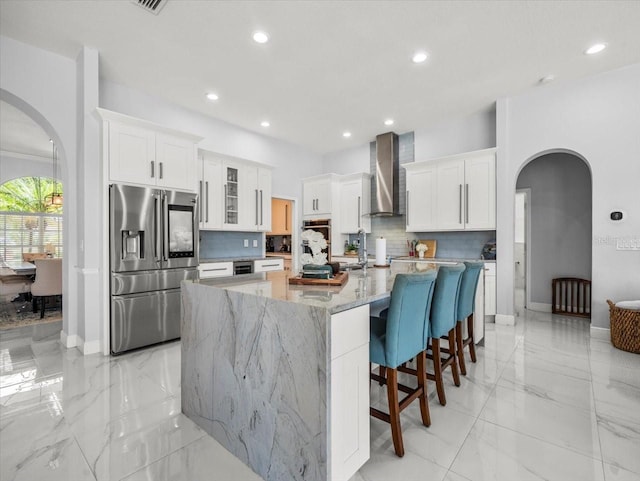1084 Berkshire Ln, Tarpon Springs, FL 34688 - kitchen featuring stainless steel refrigerator with ice dispenser, arched walkways, wall chimney exhaust hood, decorative backsplash, and recessed lighting