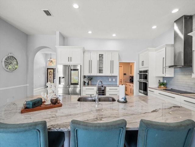 1084 Berkshire Ln, Tarpon Springs, FL 34688 - kitchen with stainless steel appliances, wall chimney exhaust hood, a sink, arched walkways, and backsplash