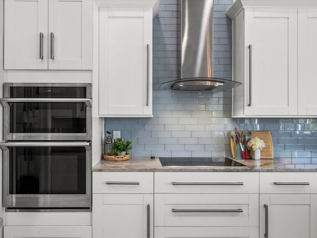 1084 Berkshire Ln, Tarpon Springs, FL 34688 - kitchen featuring wall chimney range hood, black electric stovetop, stainless steel double oven, and backsplash