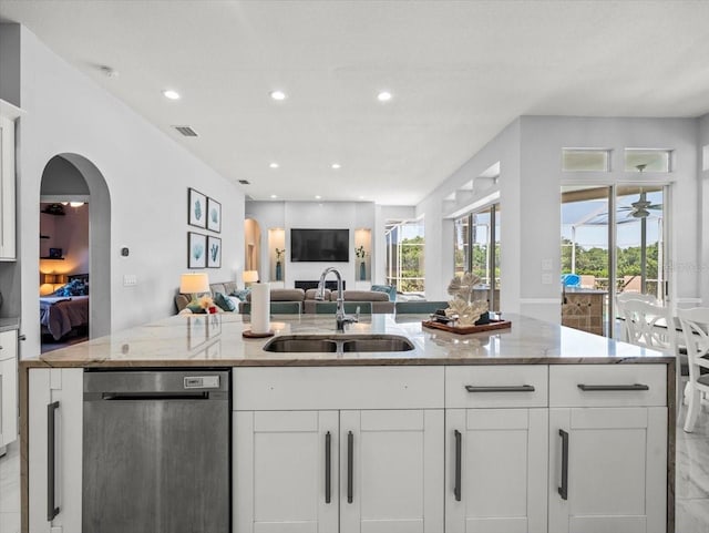 1084 Berkshire Ln, Tarpon Springs, FL 34688 - kitchen featuring stainless steel dishwasher, a sink, open floor plan, white cabinetry, and arched walkways
