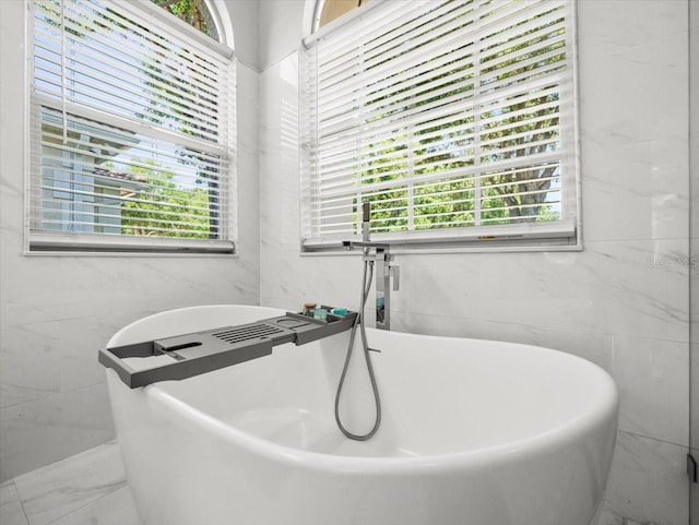 1084 Berkshire Ln, Tarpon Springs, FL 34688 - full bathroom featuring healthy amount of natural light, a soaking tub, tile walls, and marble finish flooring