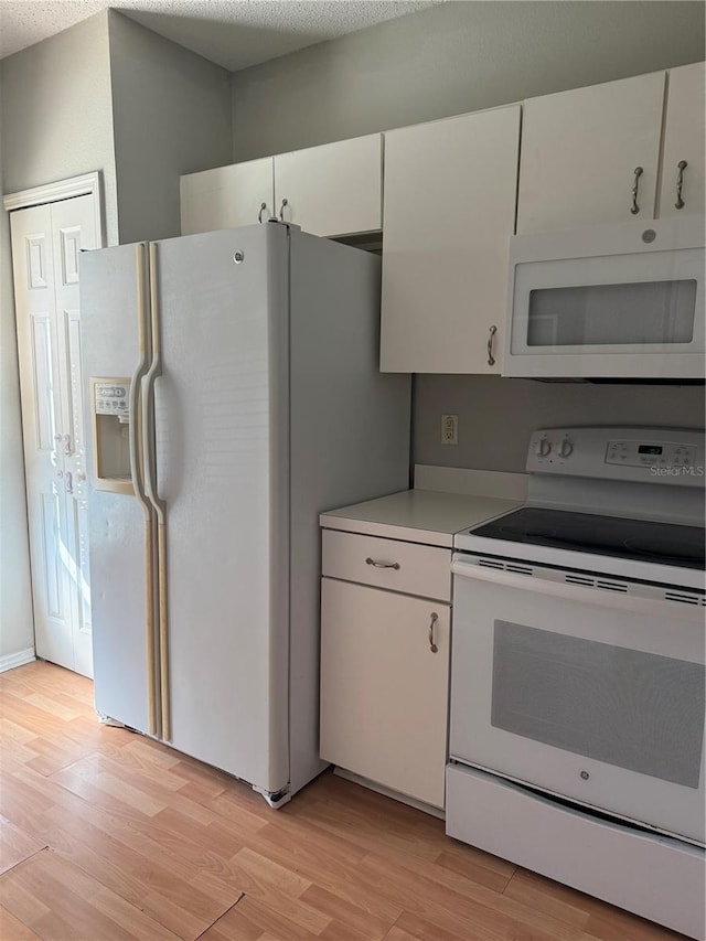 kitchen with white cabinetry, light wood finished floors, white appliances, and light countertops