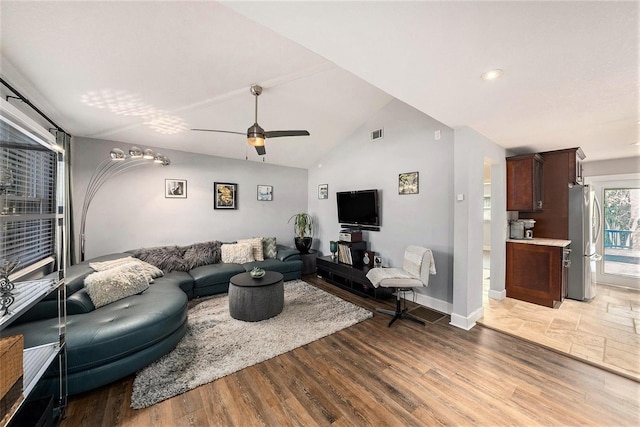 living area with lofted ceiling, visible vents, baseboards, wood finished floors, and a ceiling fan