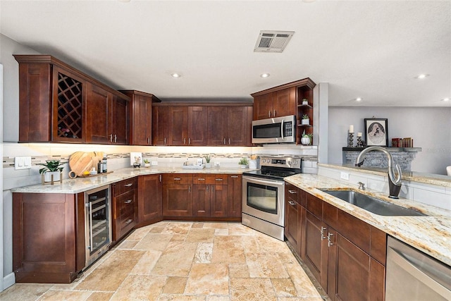 kitchen featuring a sink, stainless steel appliances, wine cooler, stone tile floors, and visible vents