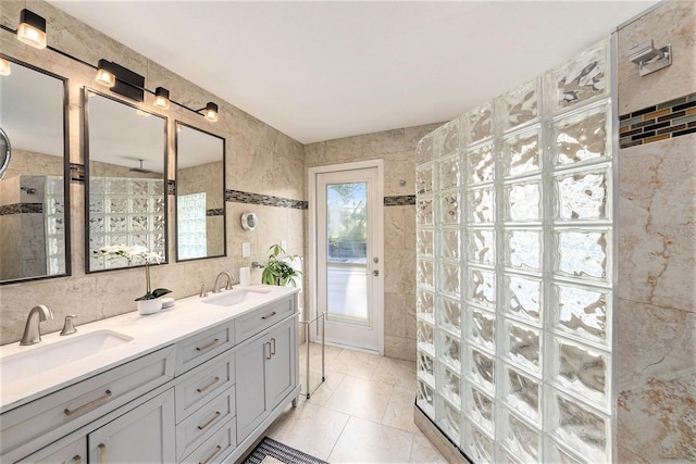 full bathroom featuring tile walls, a walk in shower, double vanity, and a sink
