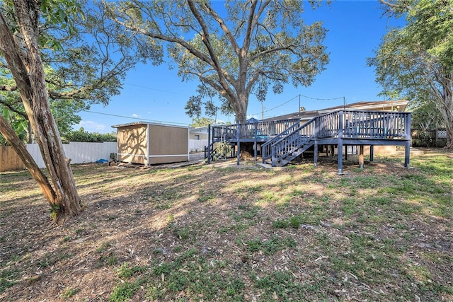 view of yard with a deck, an outdoor structure, fence, a storage shed, and stairs
