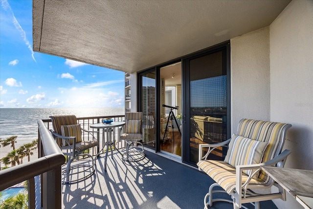 balcony featuring a view of the beach and a water view