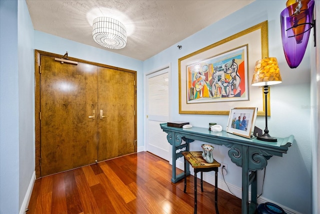 entryway with baseboards, a chandelier, and wood finished floors