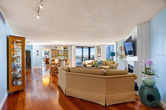 living area with a fireplace, dark wood-style flooring, baseboards, and a textured ceiling