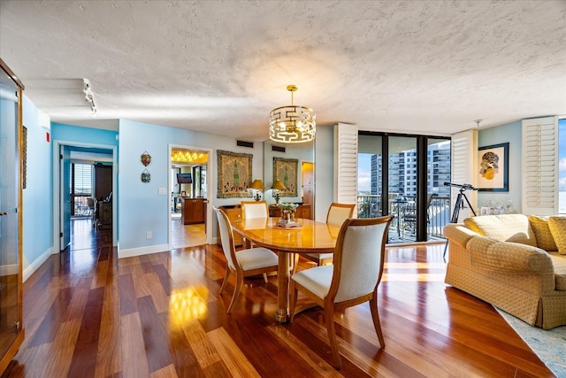 dining area with baseboards, an inviting chandelier, wood finished floors, and a textured ceiling