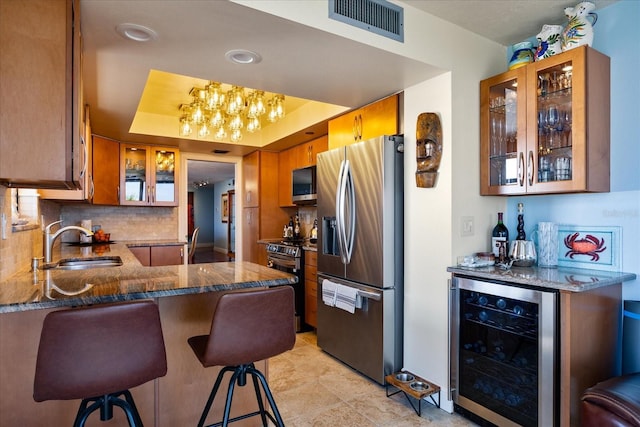 kitchen with visible vents, a sink, appliances with stainless steel finishes, wine cooler, and brown cabinetry