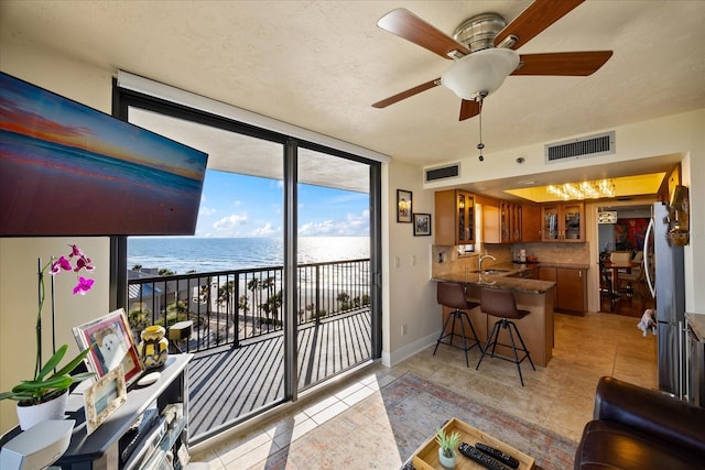 interior space featuring a water view, a wealth of natural light, visible vents, and expansive windows