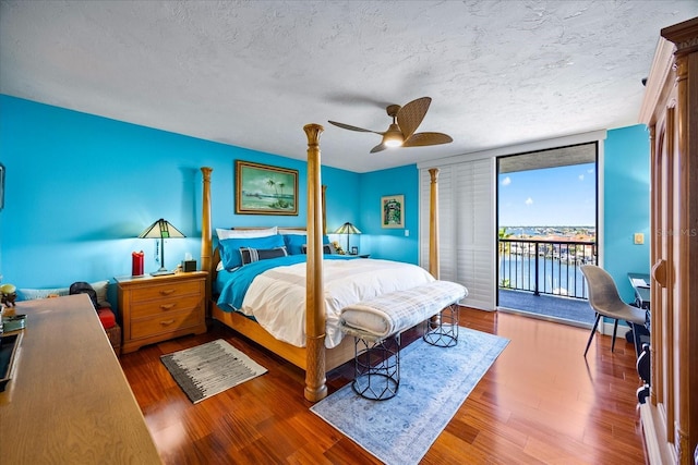 bedroom with floor to ceiling windows, access to exterior, a textured ceiling, and wood finished floors