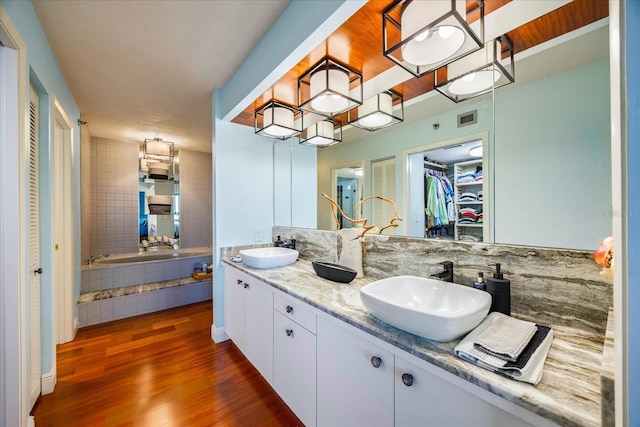full bathroom with wood finished floors, double vanity, a sink, and visible vents