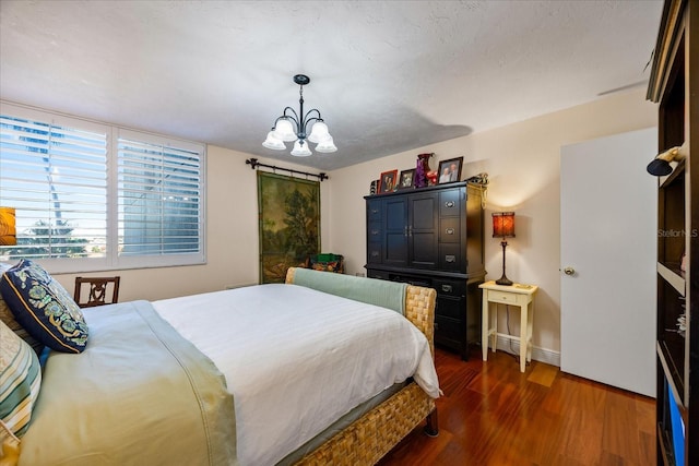 bedroom with wood finished floors, an inviting chandelier, and baseboards
