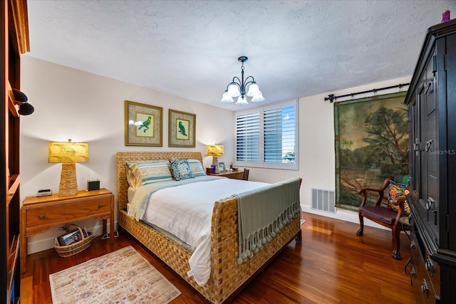 bedroom with a chandelier, wood finished floors, baseboards, and visible vents